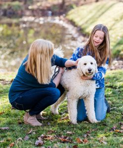 A therapist and her teen client  petting a dog during an outdoor session