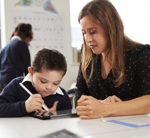 A woman watching her son draw a picture on a tablet