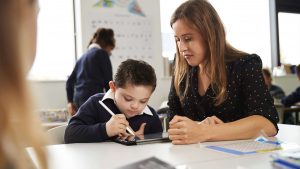 A woman watching her son draw a picture on a tablet