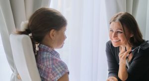 A therapist smiles while listening to a young girl speak