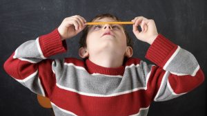 Bored student balancing a pencil on his nose